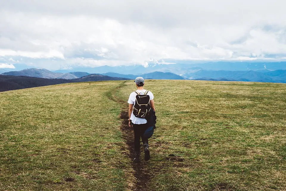 Man walking down path in open landscape