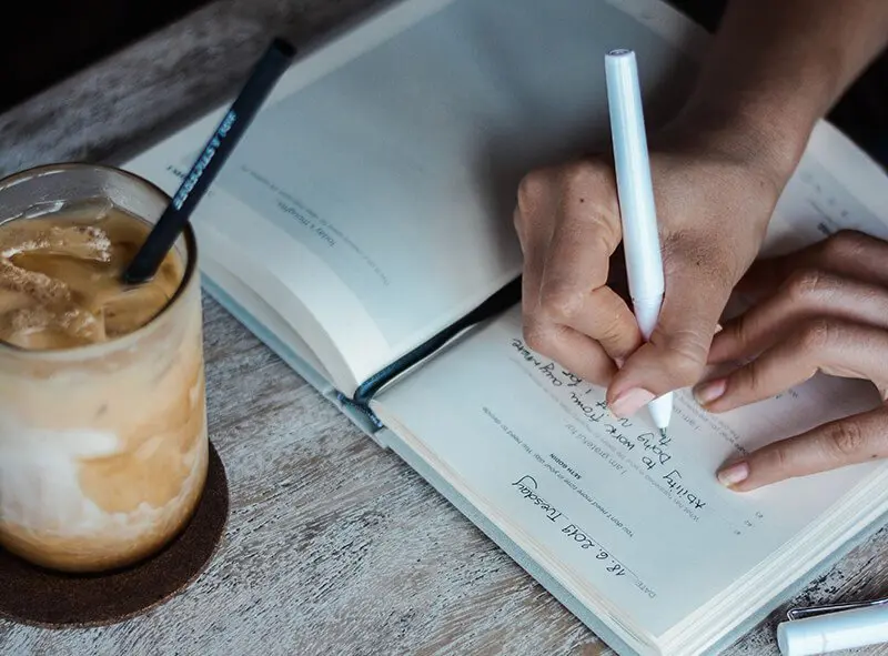Closeup of woman writing into her journal