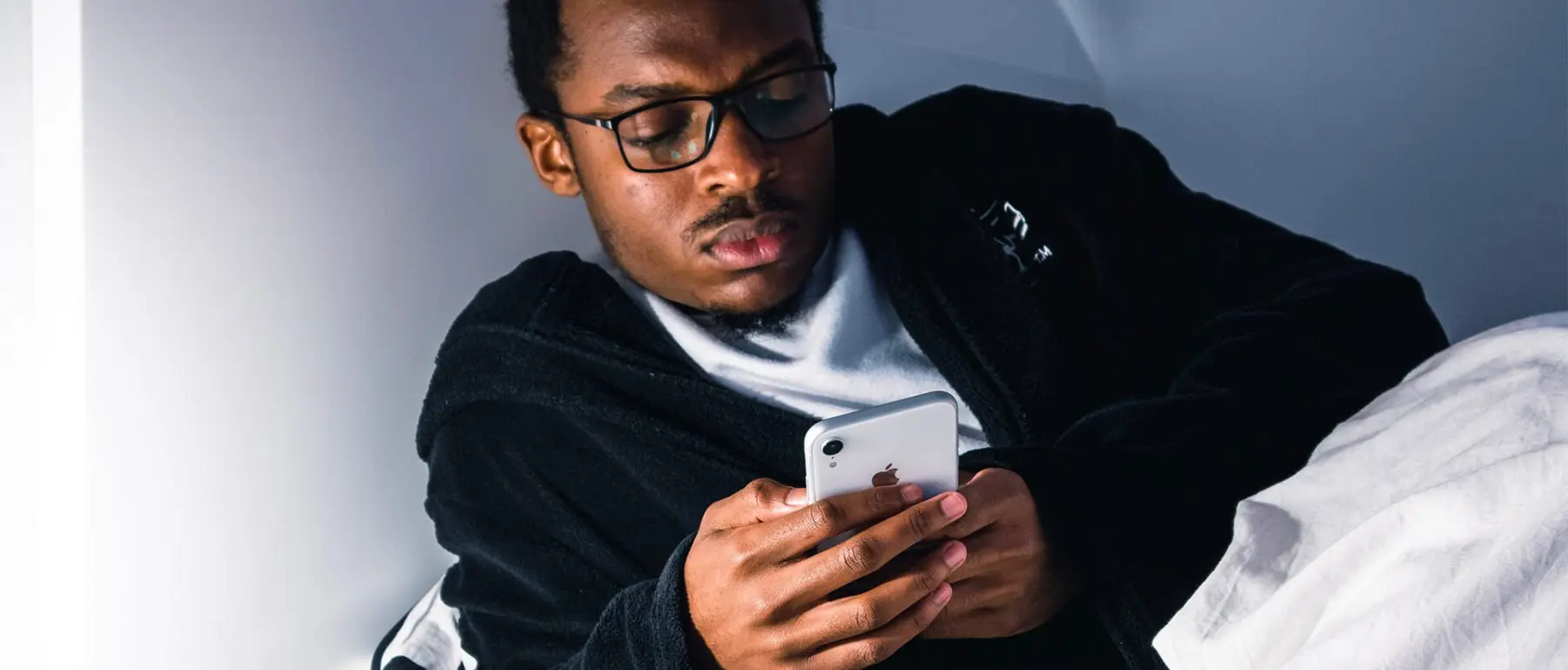 a man in glasses looking at a cell phone.