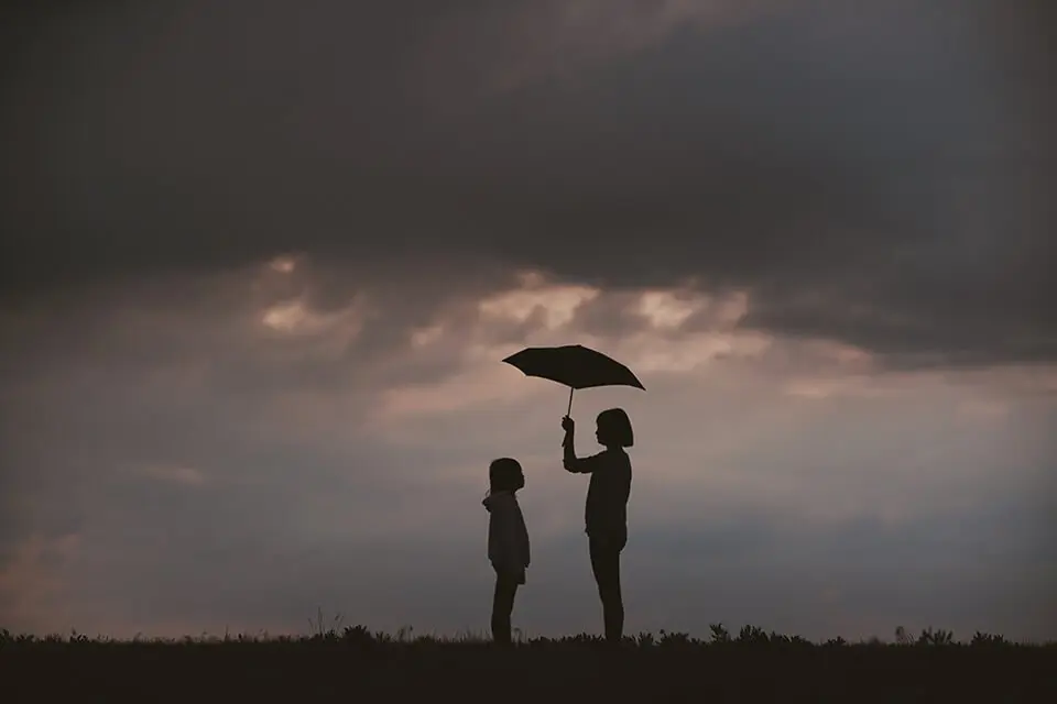 Girl holding up umbrella for little sister