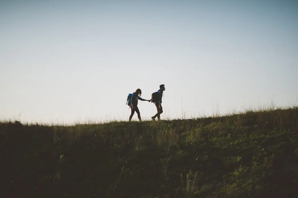 Man leading a woman, hand-in-hand, on a hike