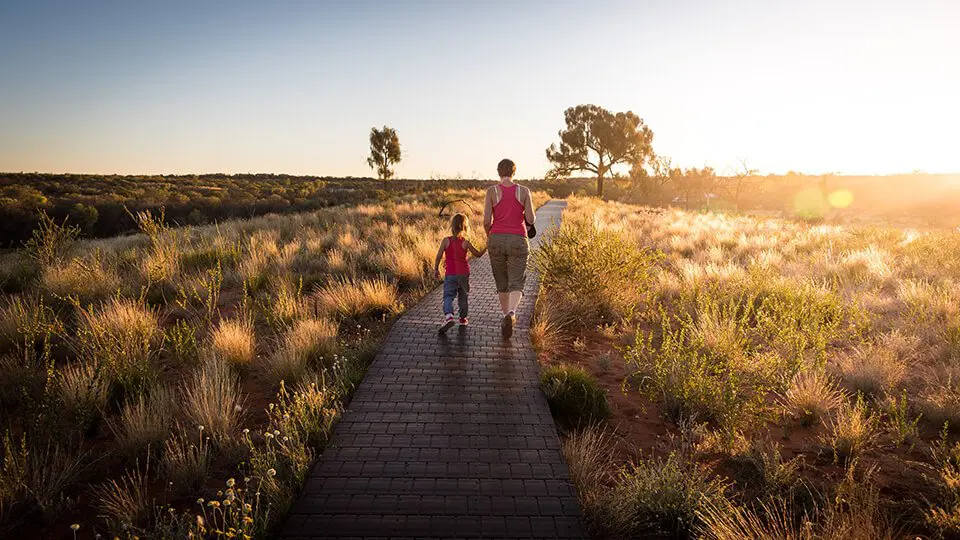 Father walking down path with daughter near the setting sun