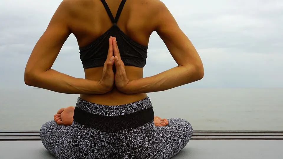 Woman sitting and meditating wearing meditation clothing