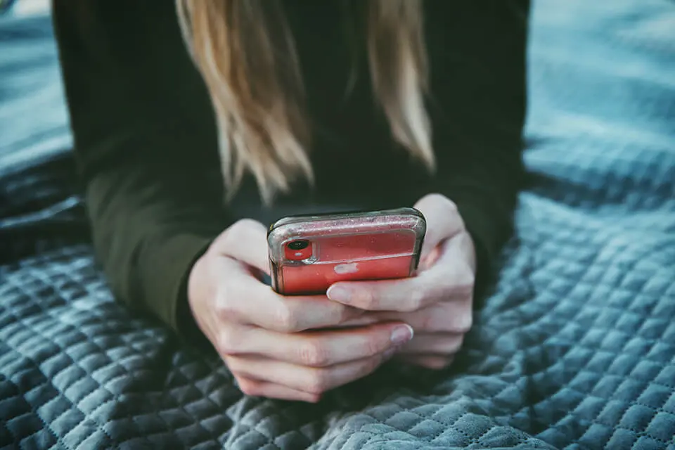 Woman lying in bed reading news on phone