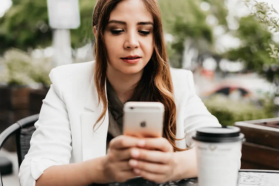 Woman having coffee while doomscrolling on her phone