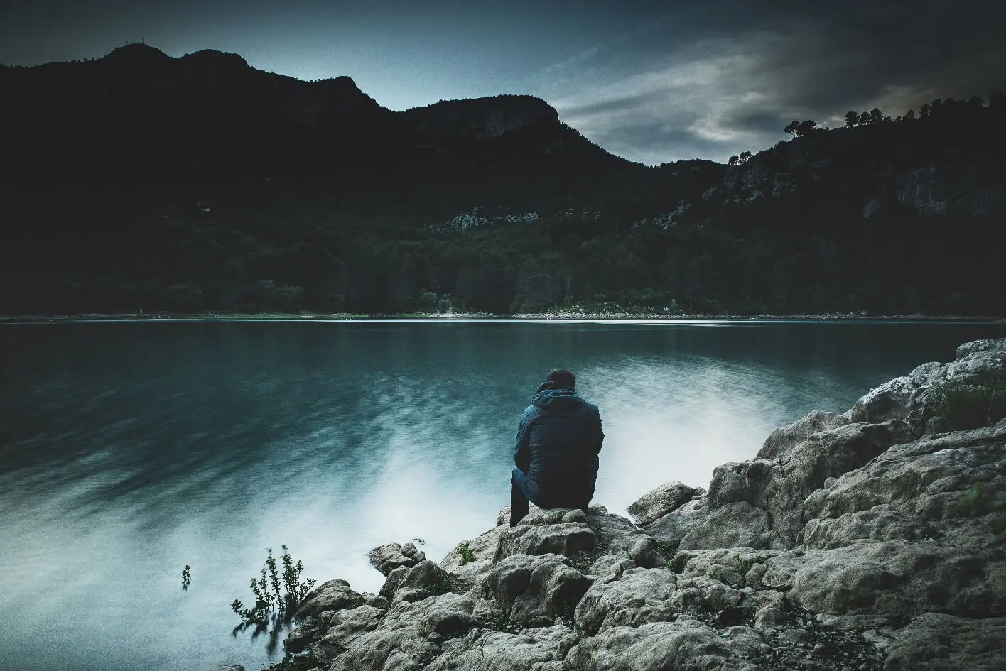 Man sitting in silence near a lake