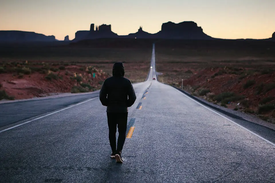 Man walking down an empty road with his hoodie on