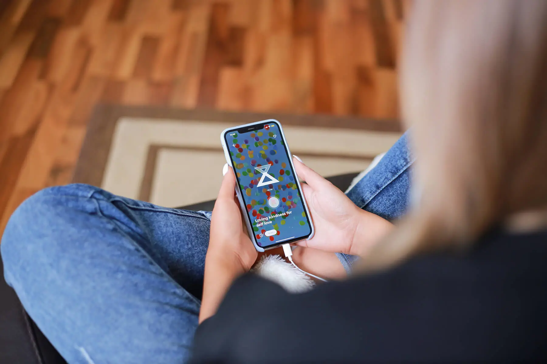Woman sitting on couch listening to guided meditation on her phone
