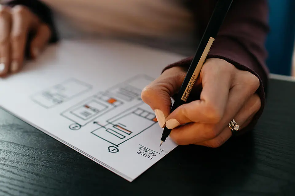a person writing on a piece of paper with a pencil.