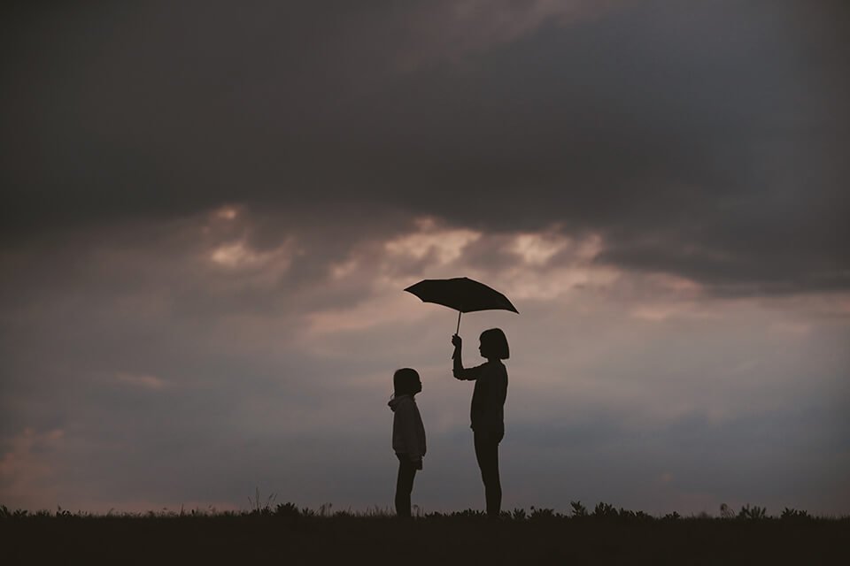 Woman holding out umbrella for child