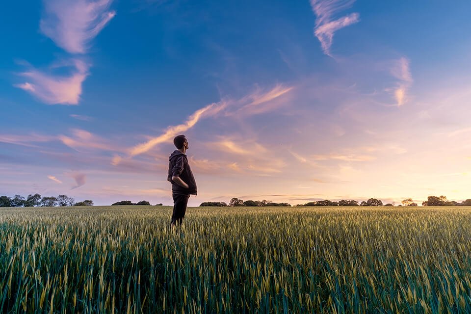 Man looking up in the sky as the sun sets