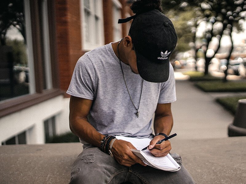 Man writing in his journal, outside on a bench