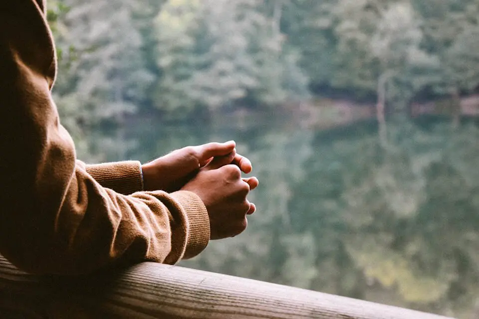 Person standing overlooking a lake, contemplating something