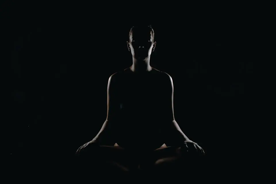 Woman sitting in the dark practicing meditation