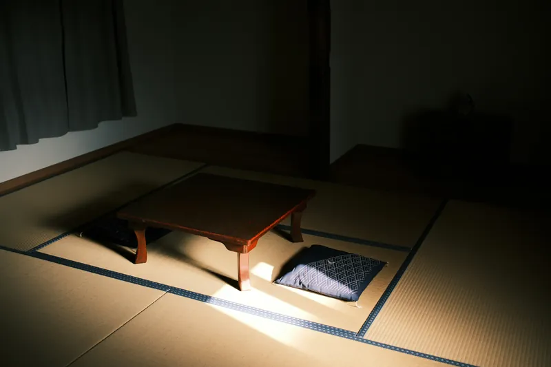 A low wooden table with cushions on tatami mats in a minimal room