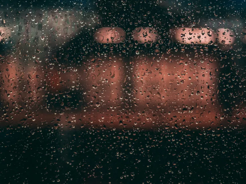 Blurred warm lights seen through a rain-streaked window, like looking at the world through brain fog.