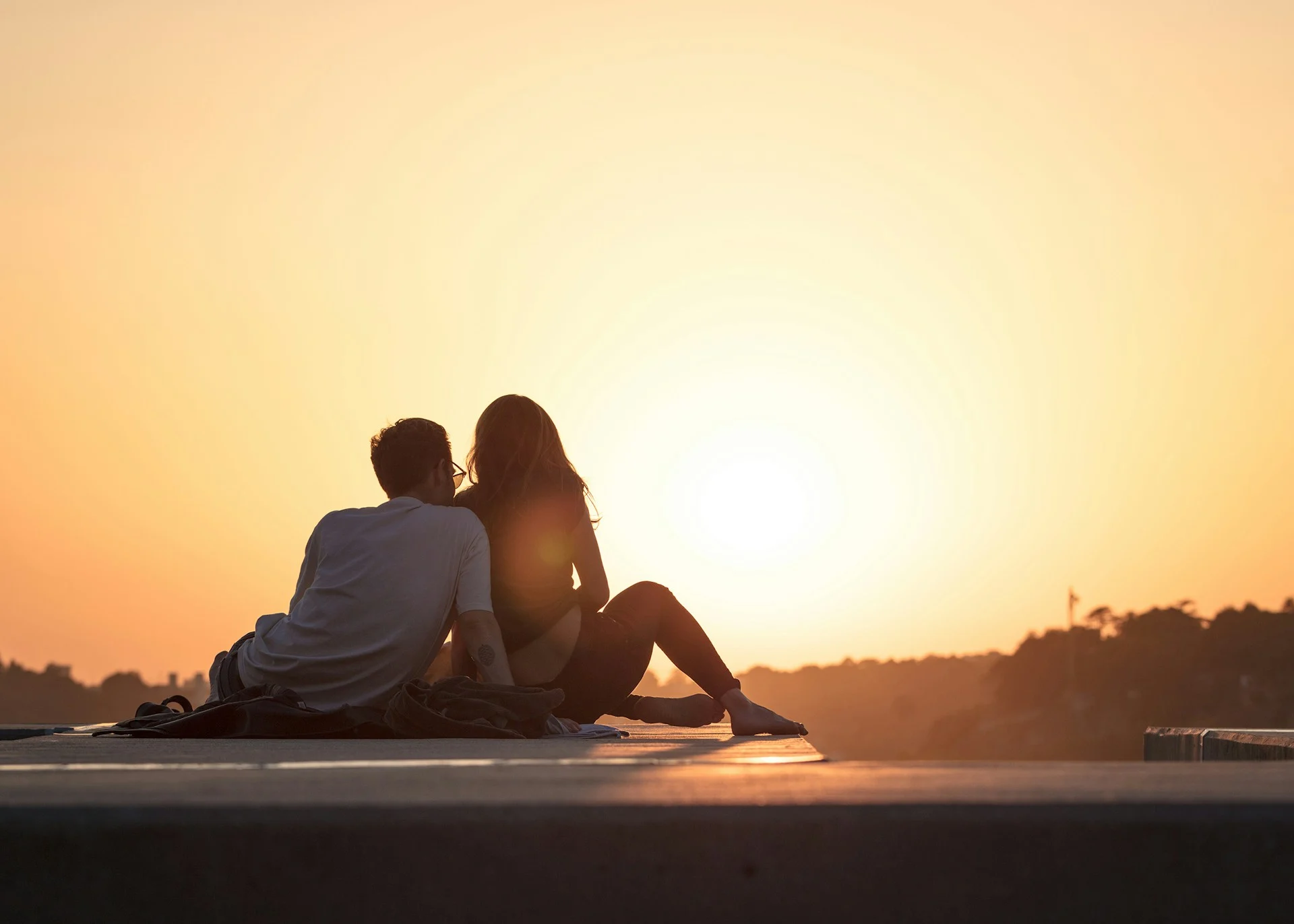 Two people sitting close together at sunset, calm and at ease
