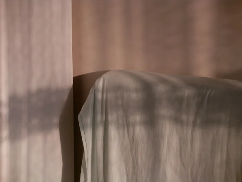 Soft shadows falling across draped linen in muted morning light