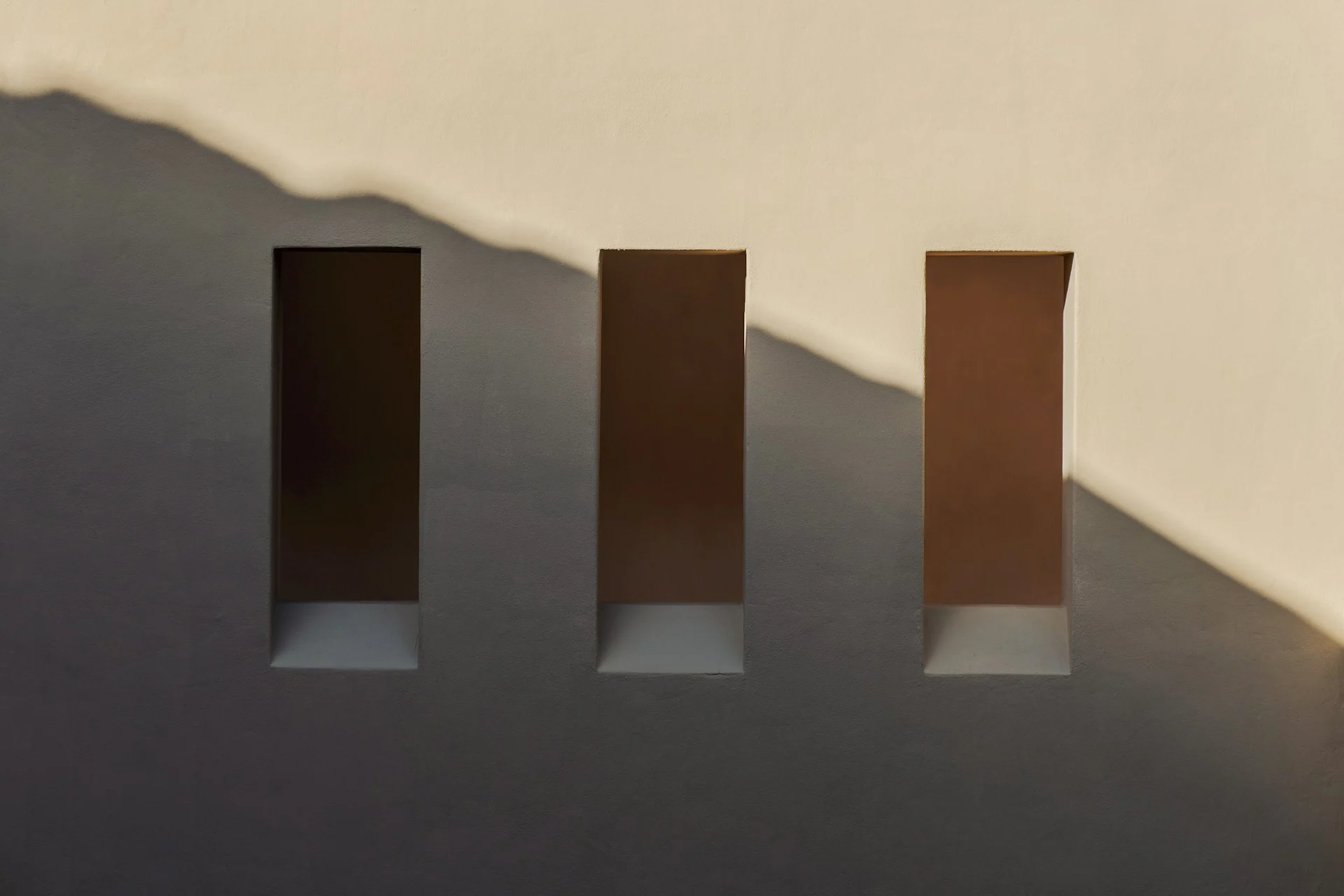 Soft warm daylight and shadow across a minimal wall, suggesting a calm break from screens.