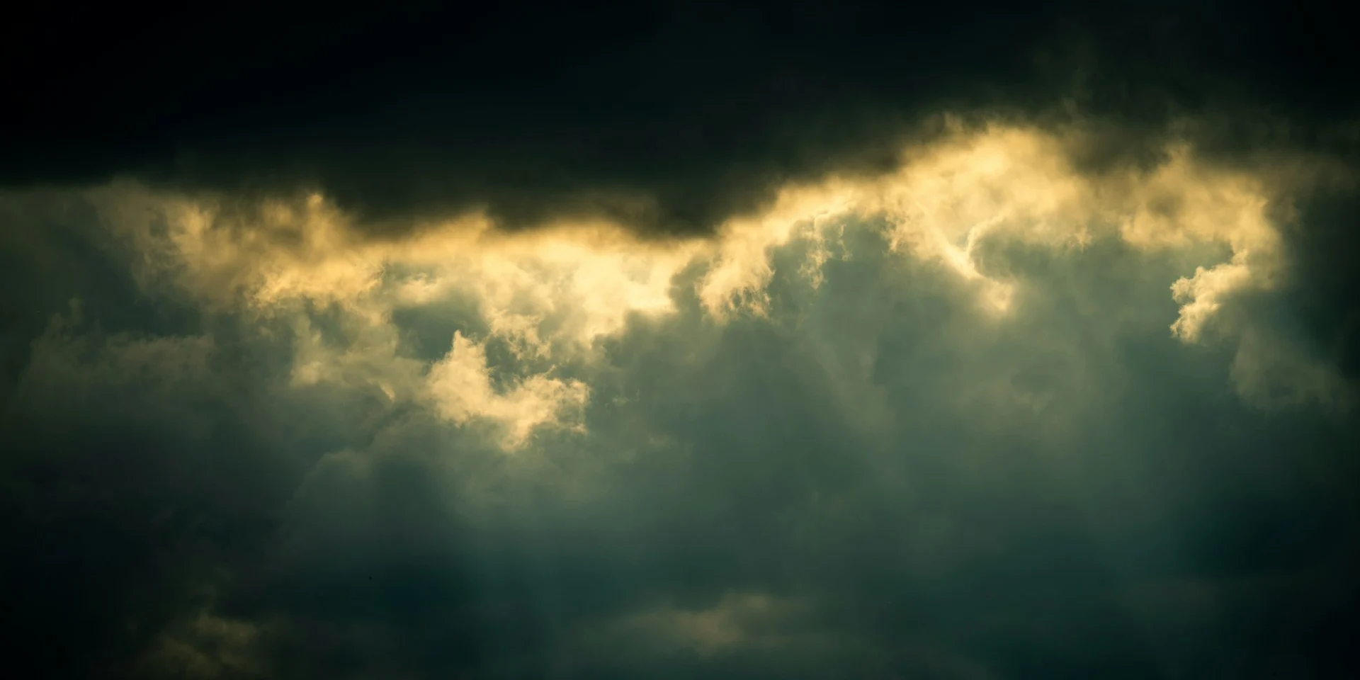 Dark storm clouds breaking open to let a band of calm light through