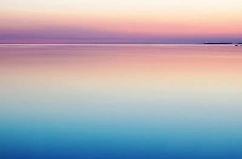 Calm, still water blending into a soft pink and blue horizon at dusk.