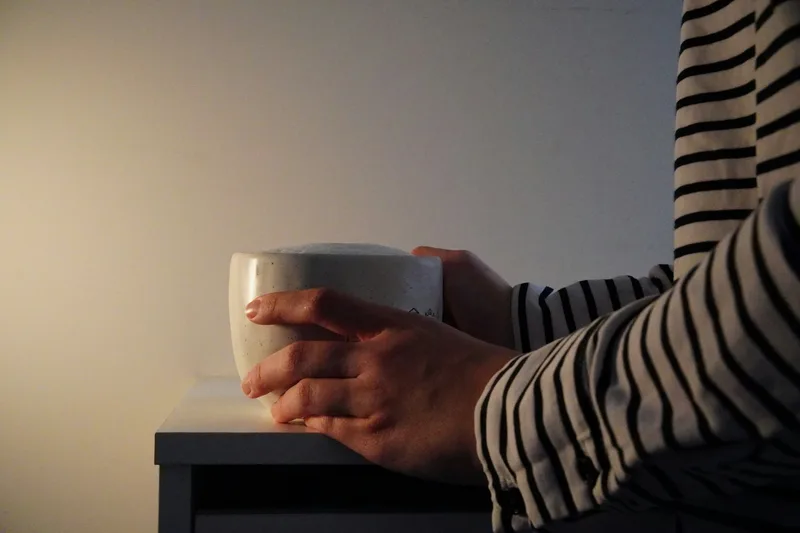 Two hands cradling a warm cup in soft light