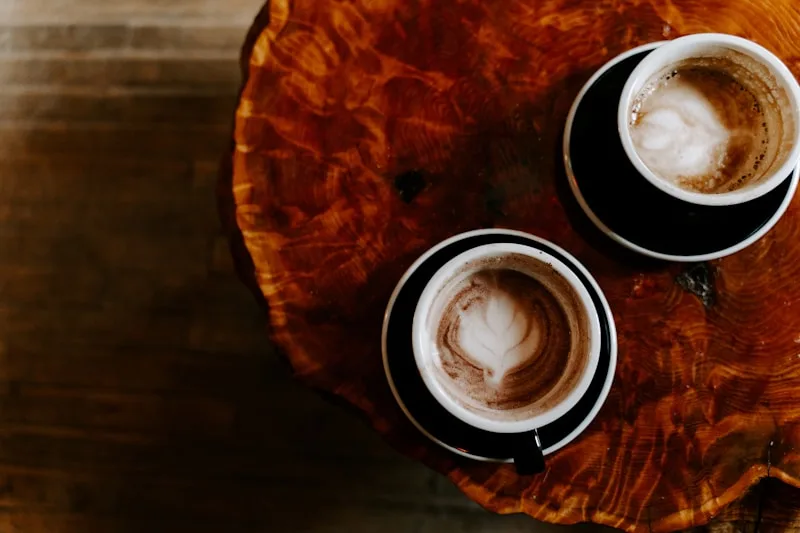 Two cups of coffee resting side by side on a wooden table