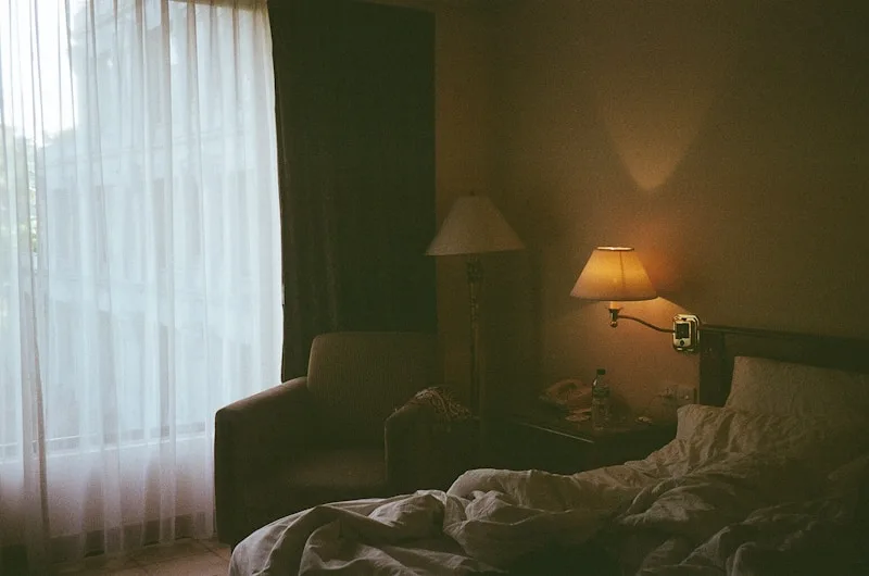 A soft, restful bedroom with sheer curtains and a warm bedside lamp