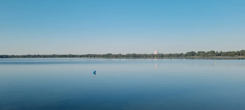 A calm, mirror-still lake under a clear sky