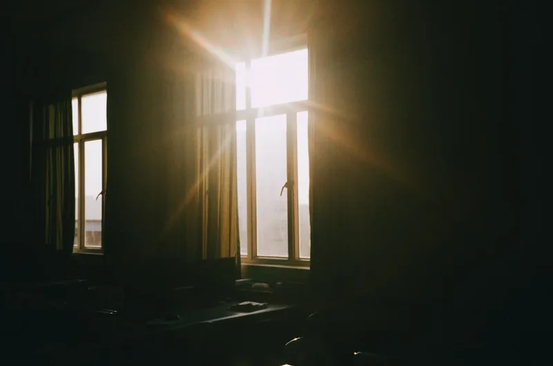 Early light streaming through a window into a dim, quiet room.