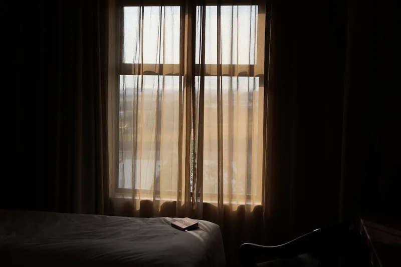 Soft morning daylight filtering through sheer curtains into a calm, dim room