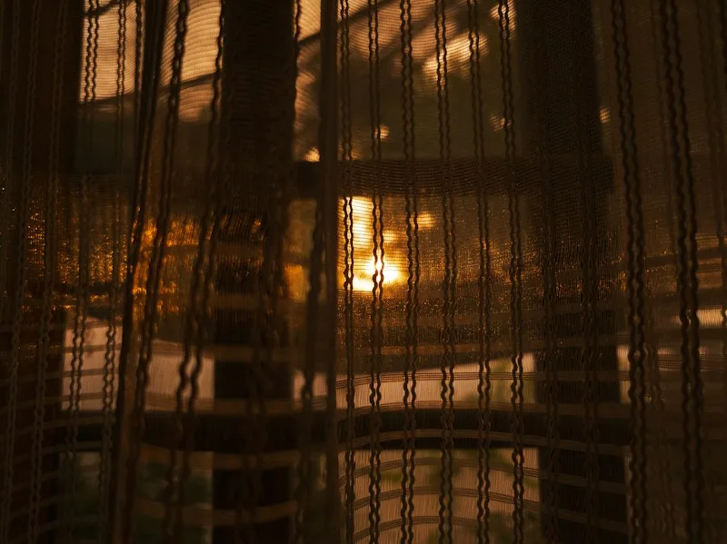 Warm light glowing through a sheer curtain at dusk