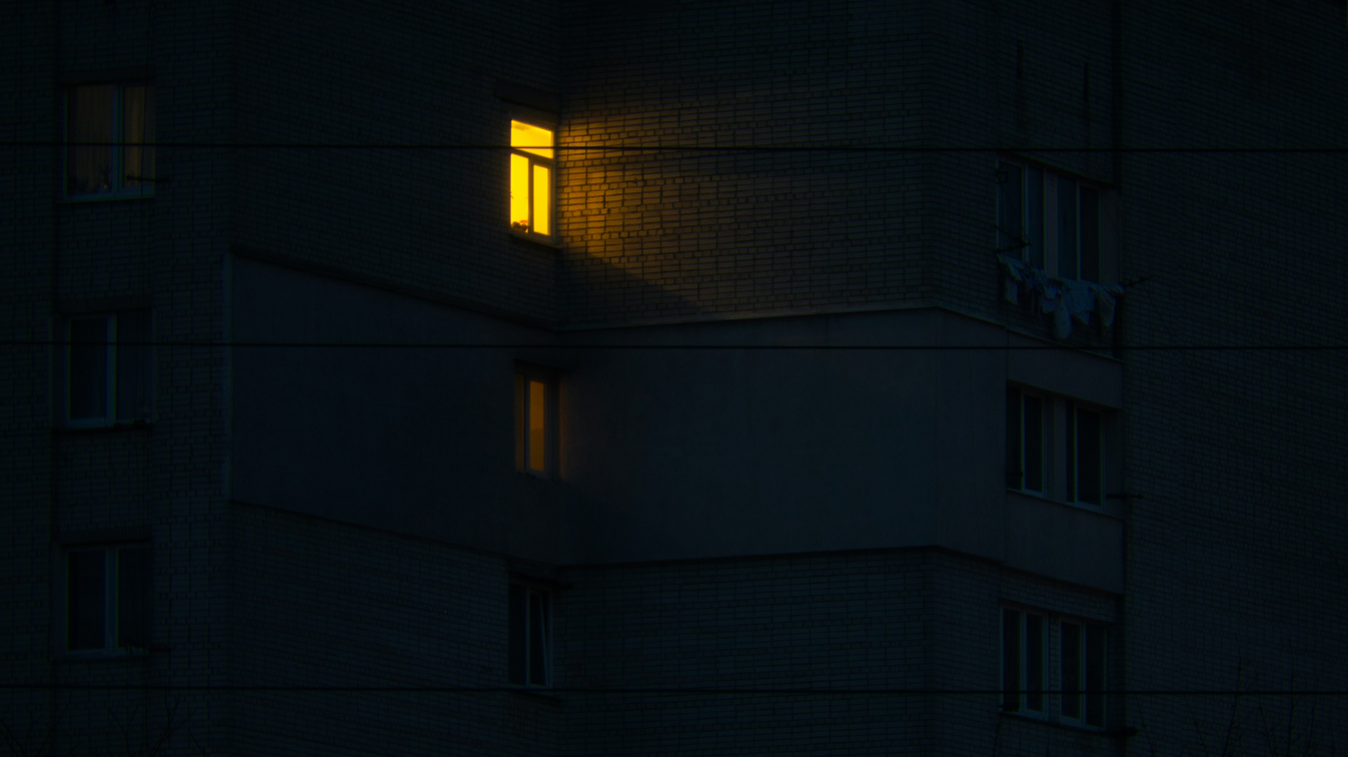 A single window lit at night against a dark building.
