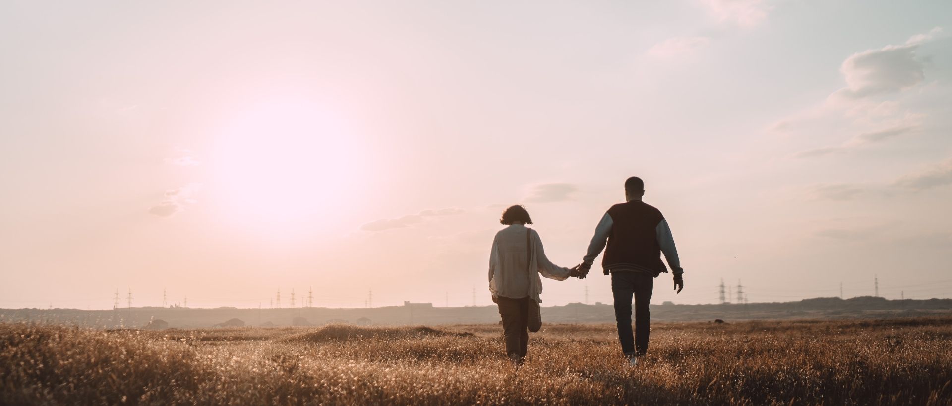 two people walking in a field holding hands.