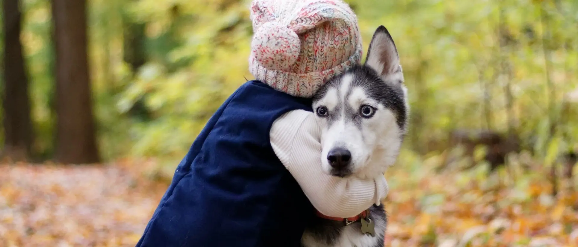 a woman holding a husky dog in her arms.