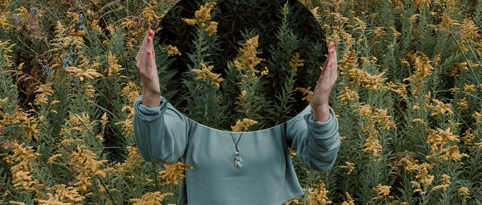 a woman standing in a field with her hands in the air.