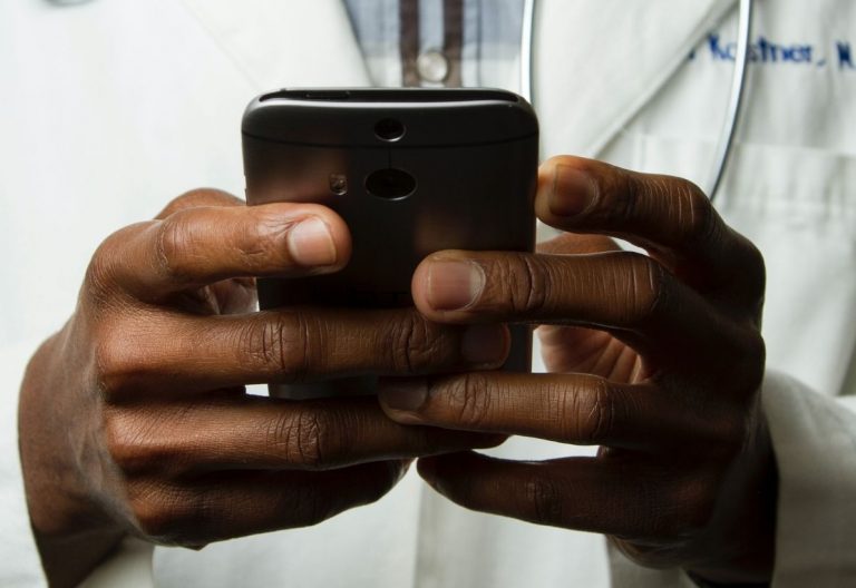 a doctor holding a smart phone in his hands.