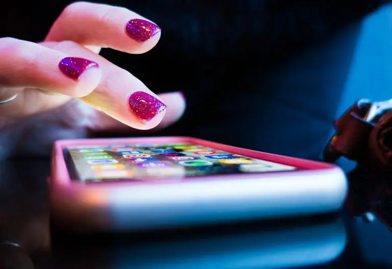 a woman's hands holding a cell phone and touching the screen.