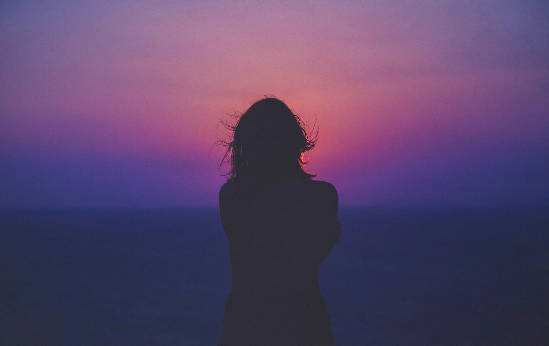 a woman standing in front of a sunset.
