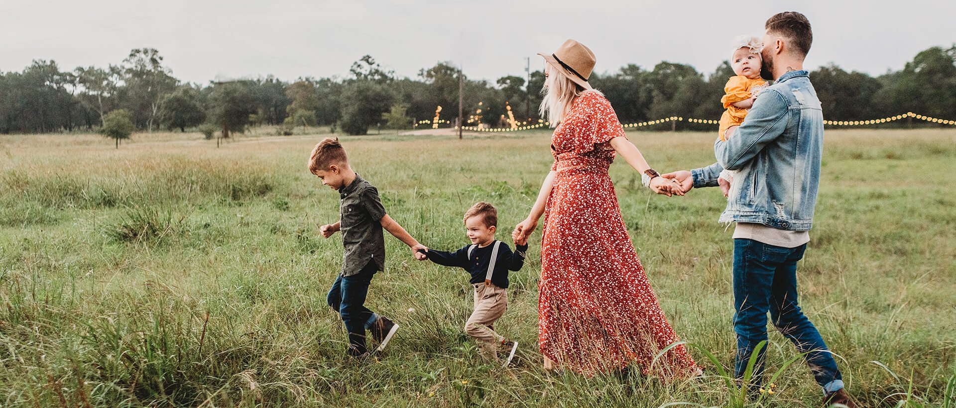 a family walking through a field holding hands.