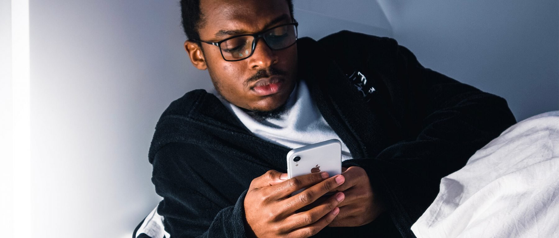 a man in glasses looking at a cell phone.