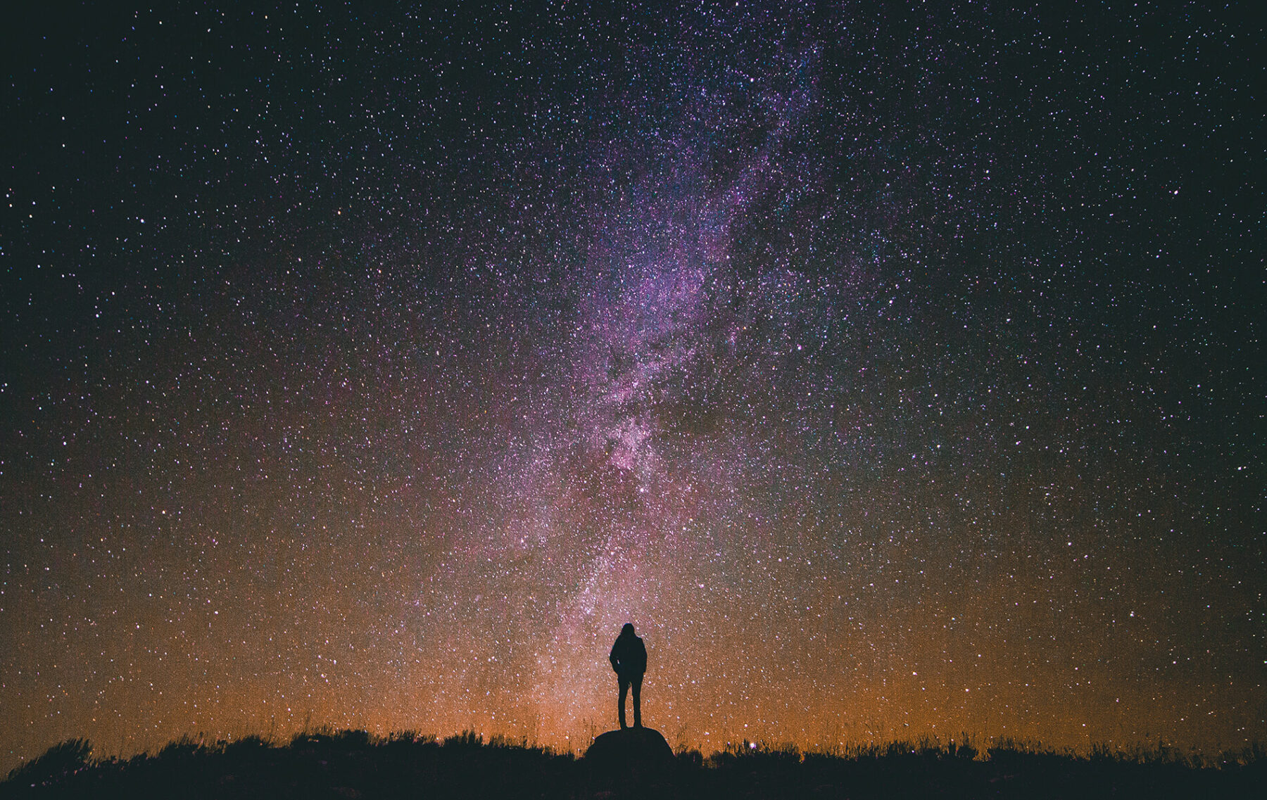 a person standing on top of a hill under a night sky.