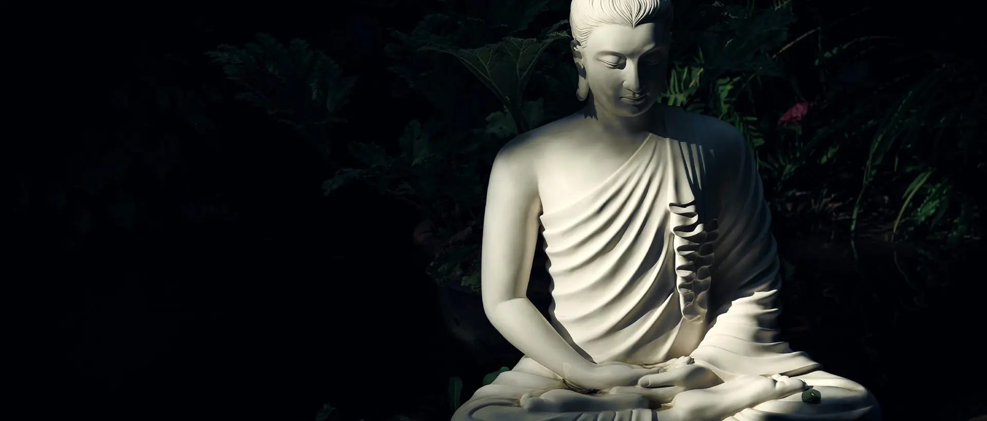 a white buddha statue sitting in the dark.