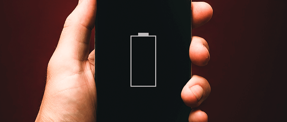 a person holding a cell phone with a battery on it.
