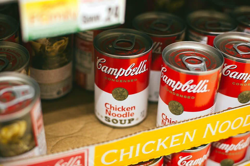 Cans of soup on a stocked shelf