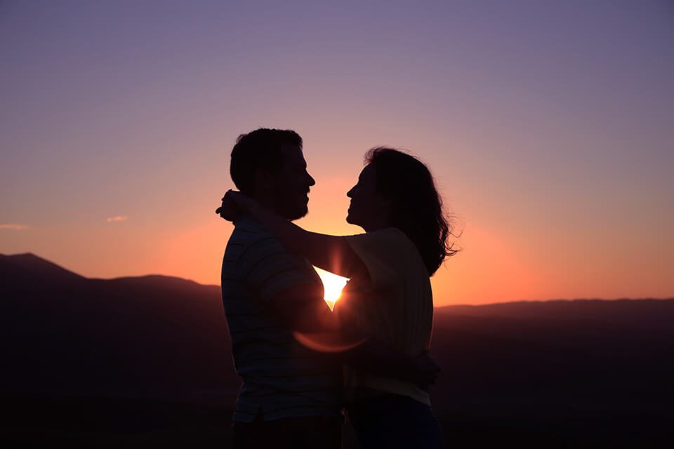 A couple embracing in front of a sunset