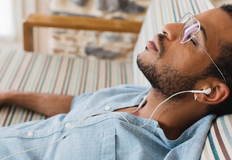a man laying on top of a bed wearing headphones.
