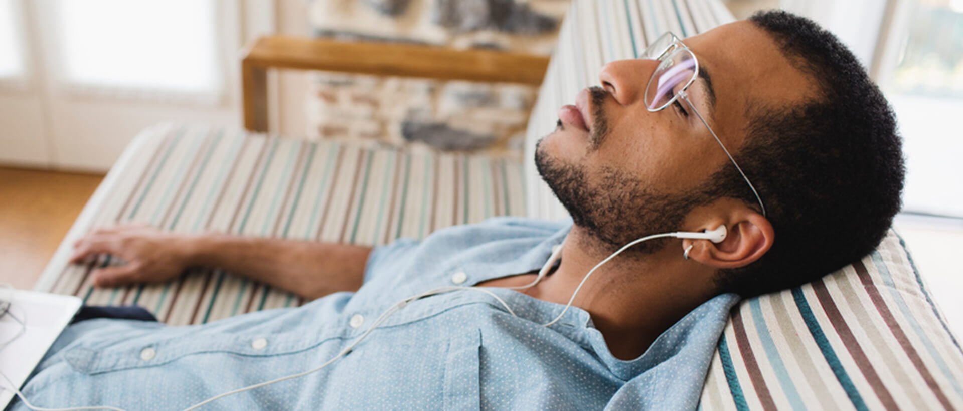 a man laying on top of a bed wearing headphones.