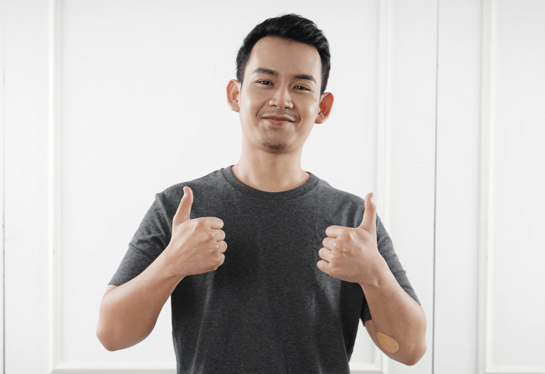 a man giving a thumbs up in front of a white wall.