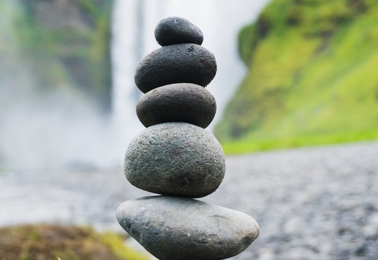 a stack of rocks sitting in front of a waterfall.